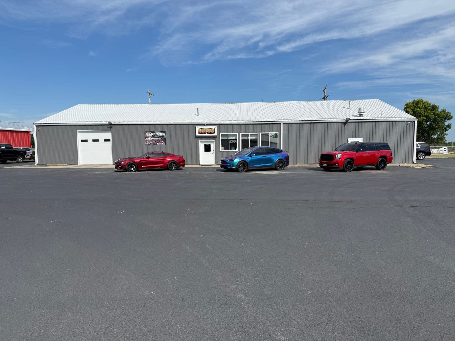 Ironwood Motorsports gray storefront in Sedalia with a red coupe, blue SUV, and red SUV parked in front
